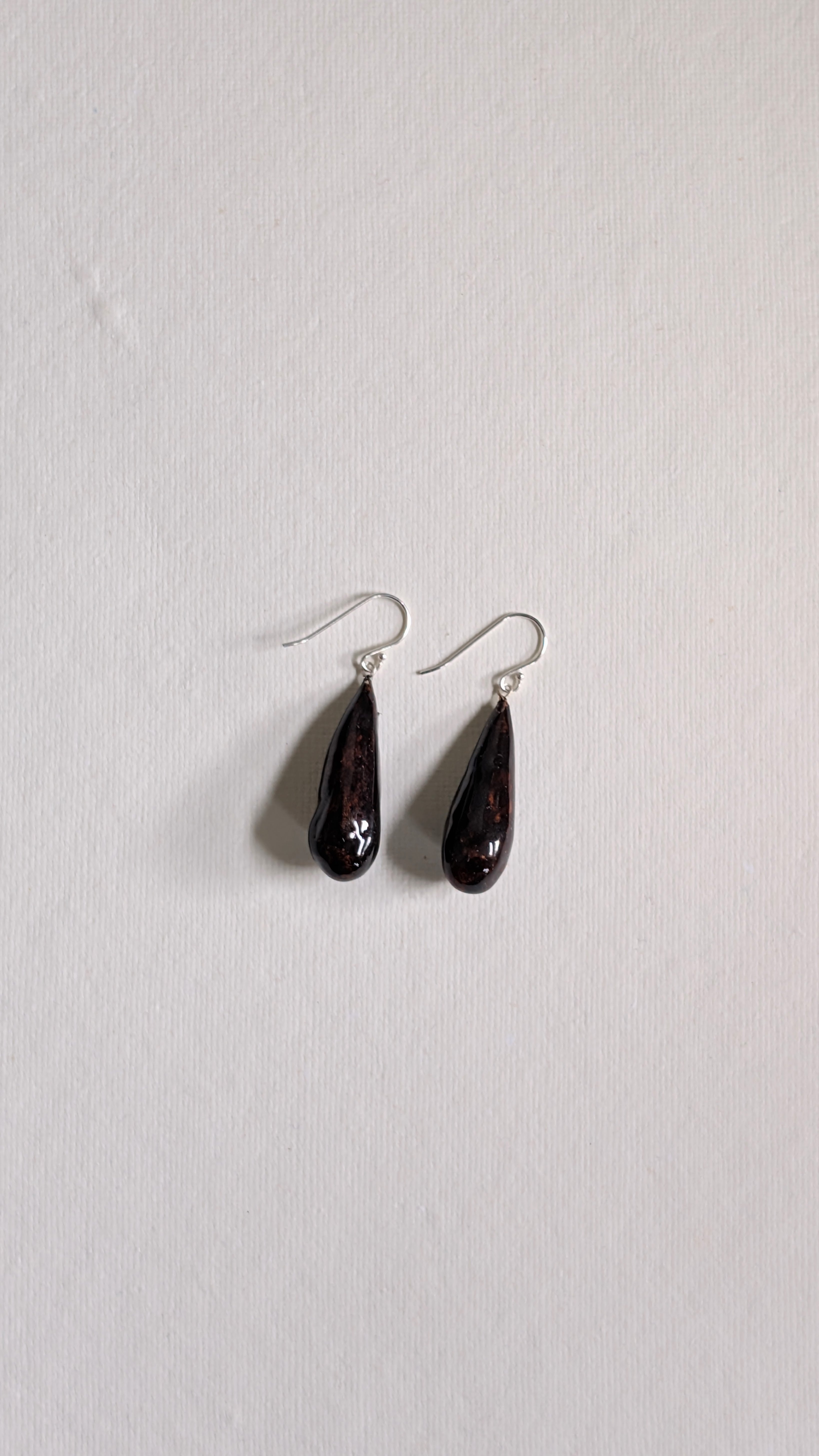 Teardrop shaped handmade ceramic earrings painted in chocolate brown and finished with sterling silver ear wires.