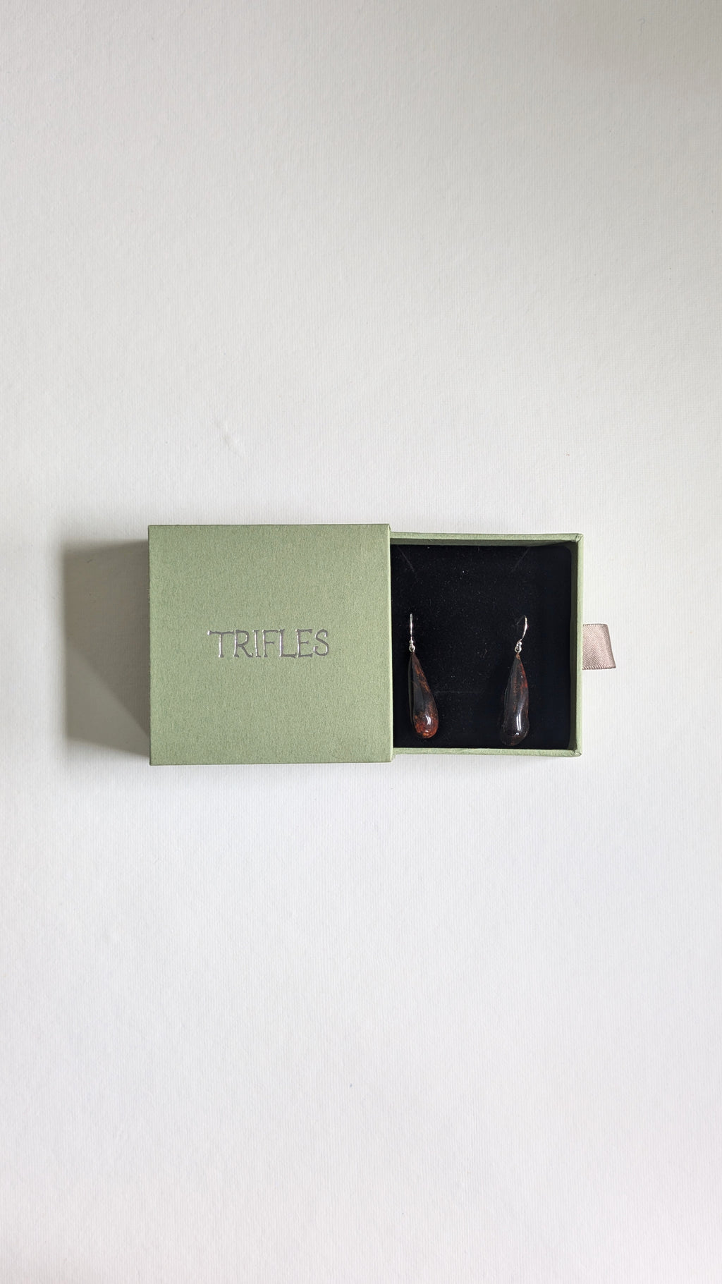 Teardrop shaped handmade ceramic earrings painted in chocolate brown and finished with sterling silver ear wires in Trifles gift box.