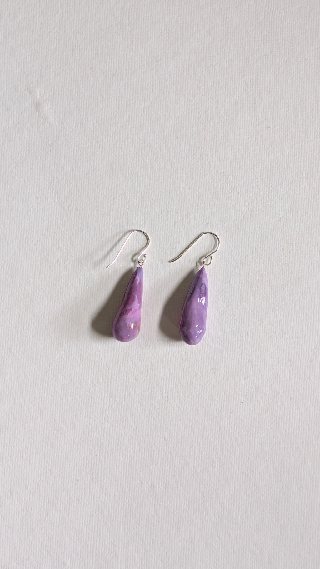 Teardrop shaped handmade ceramic earrings painted in lilac and finished with sterling silver ear wires.