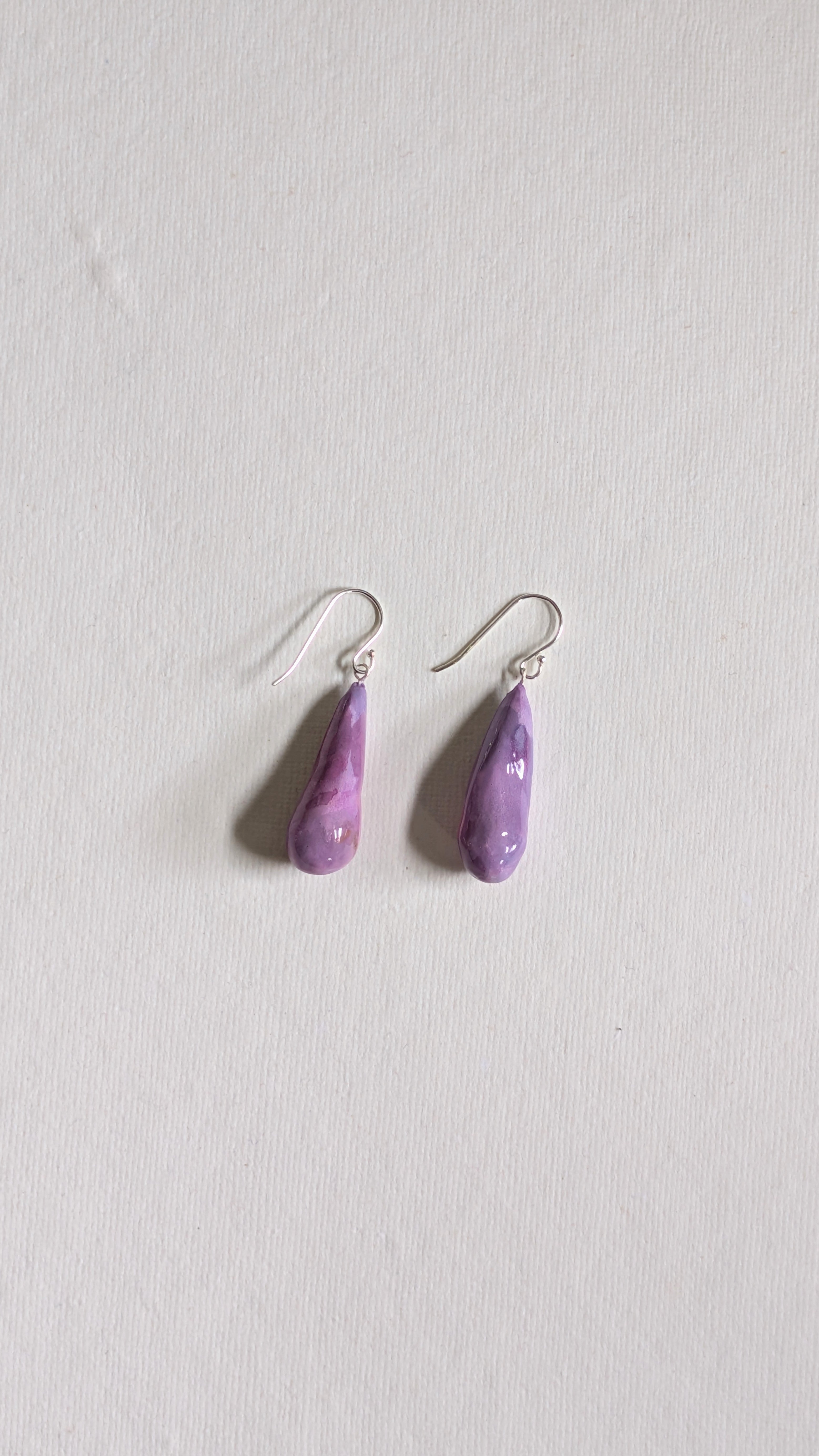 Teardrop shaped handmade ceramic earrings painted in lilac and finished with sterling silver ear wires.