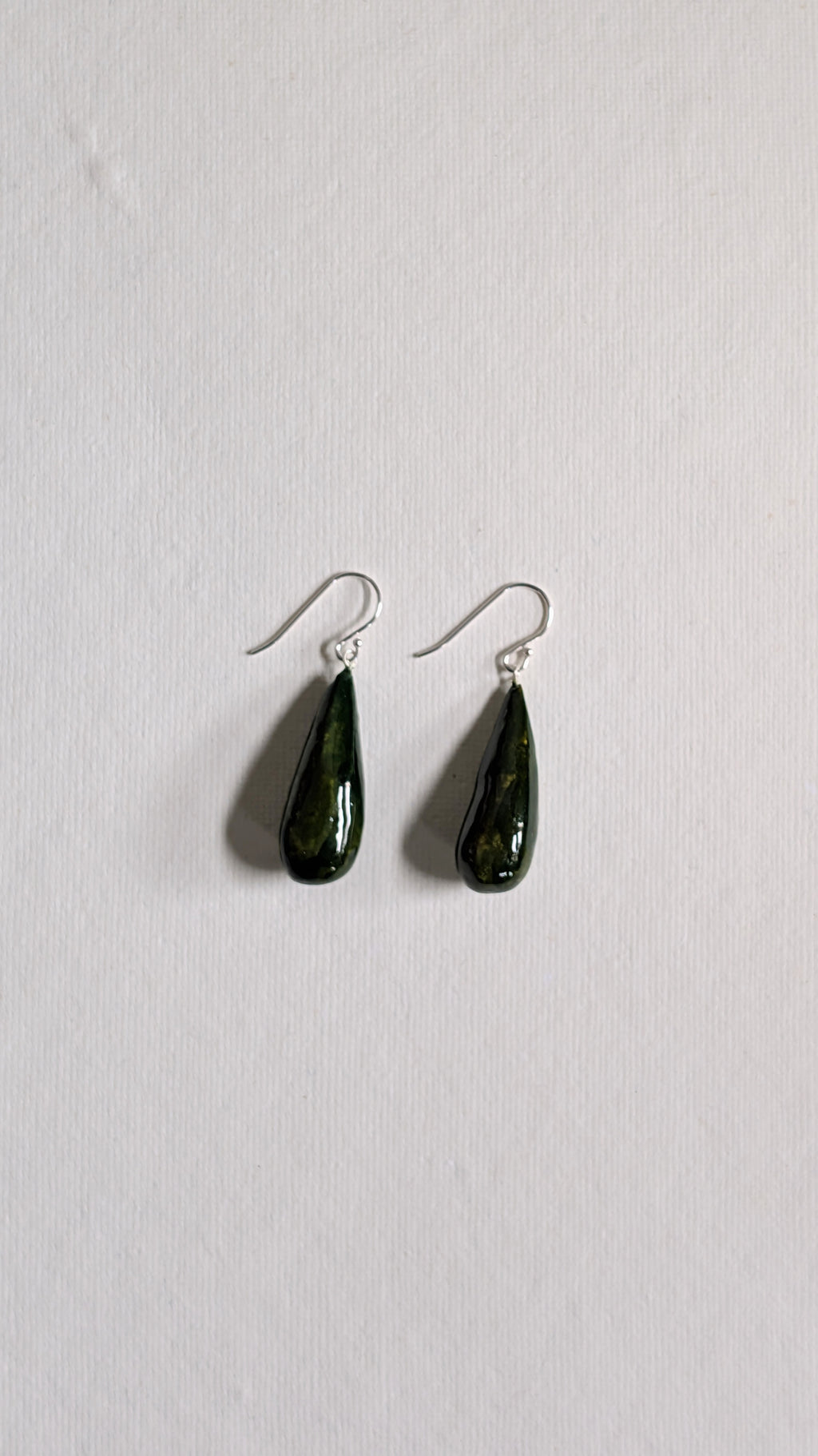 Teardrop shaped handmade ceramic earrings painted in olive green and finished with sterling silver ear wires.