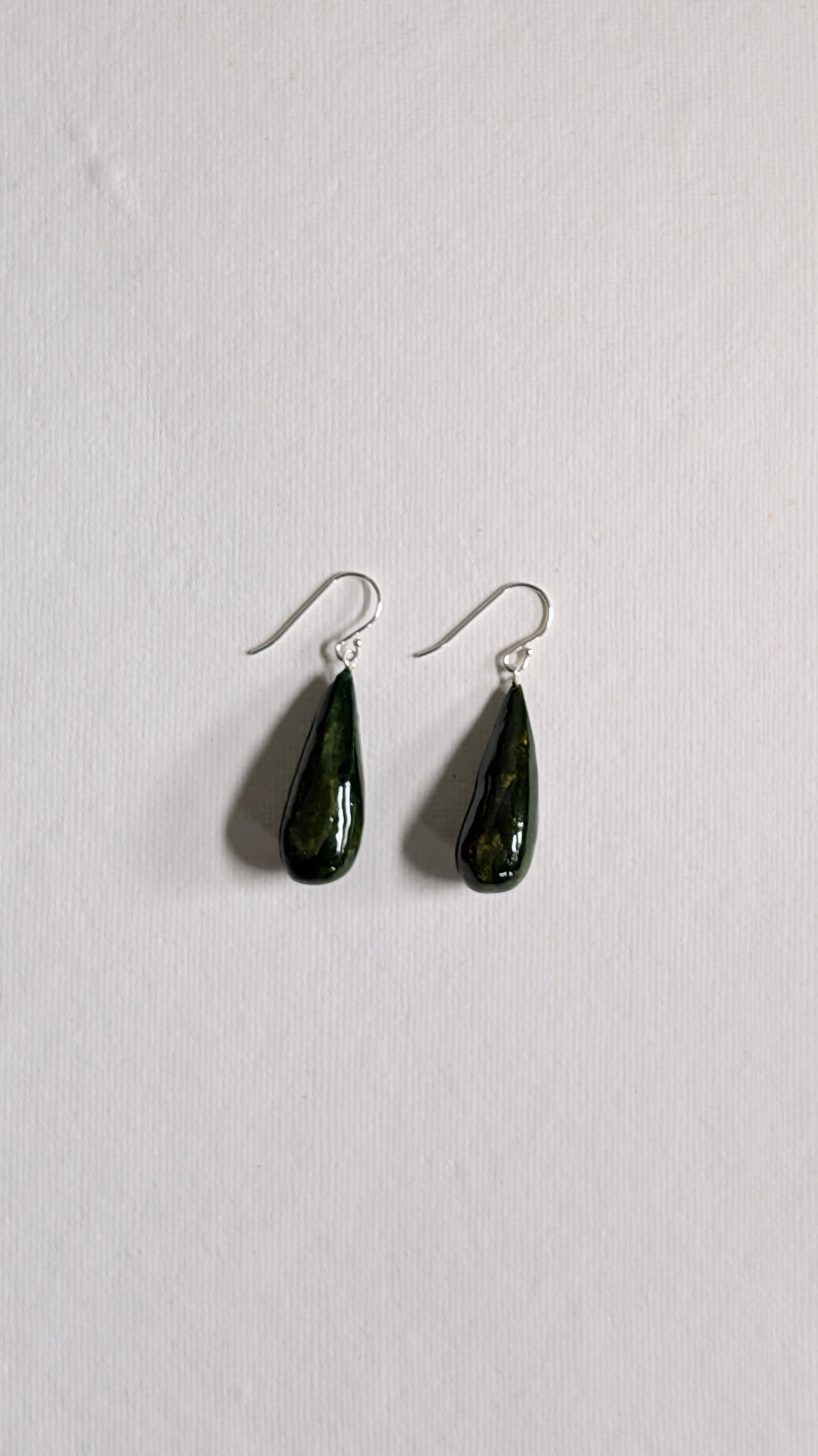 Teardrop shaped handmade ceramic earrings painted in olive green and finished with sterling silver ear wires.