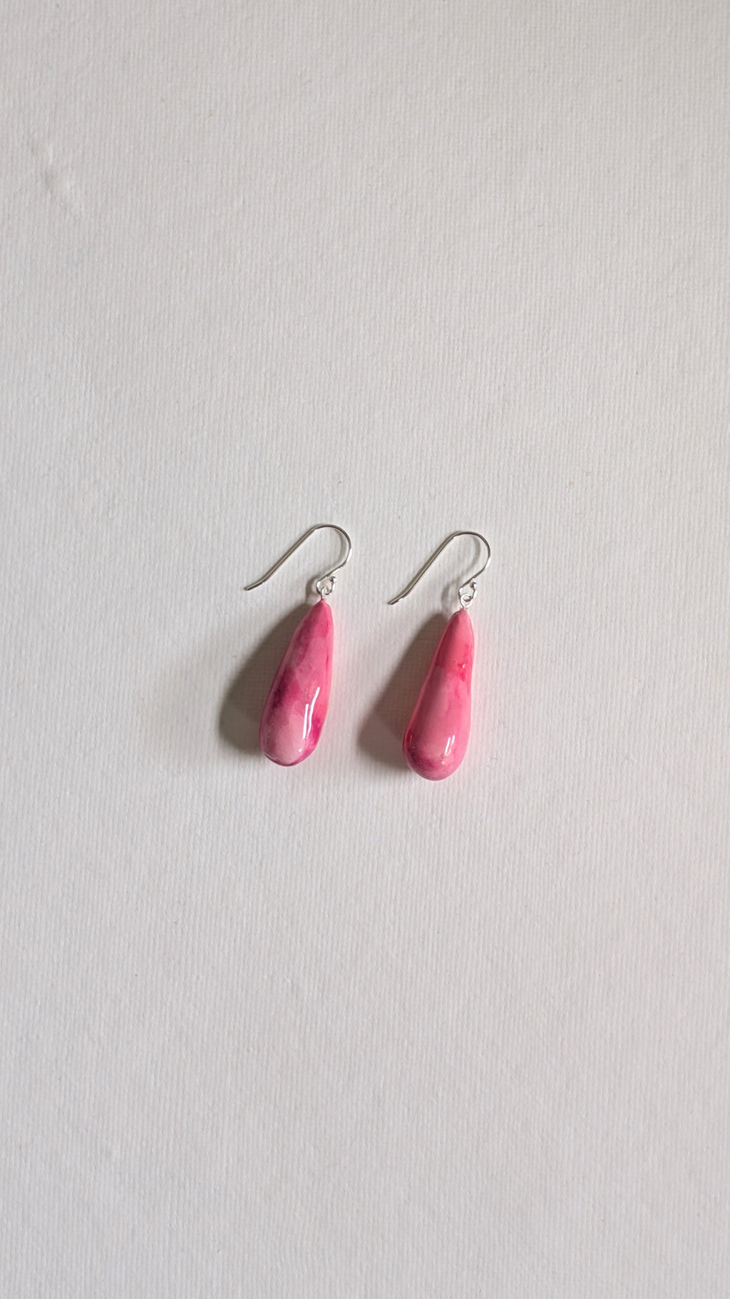 Teardrop shaped handmade ceramic earrings painted in peony pink and finished with sterling silver ear wires.