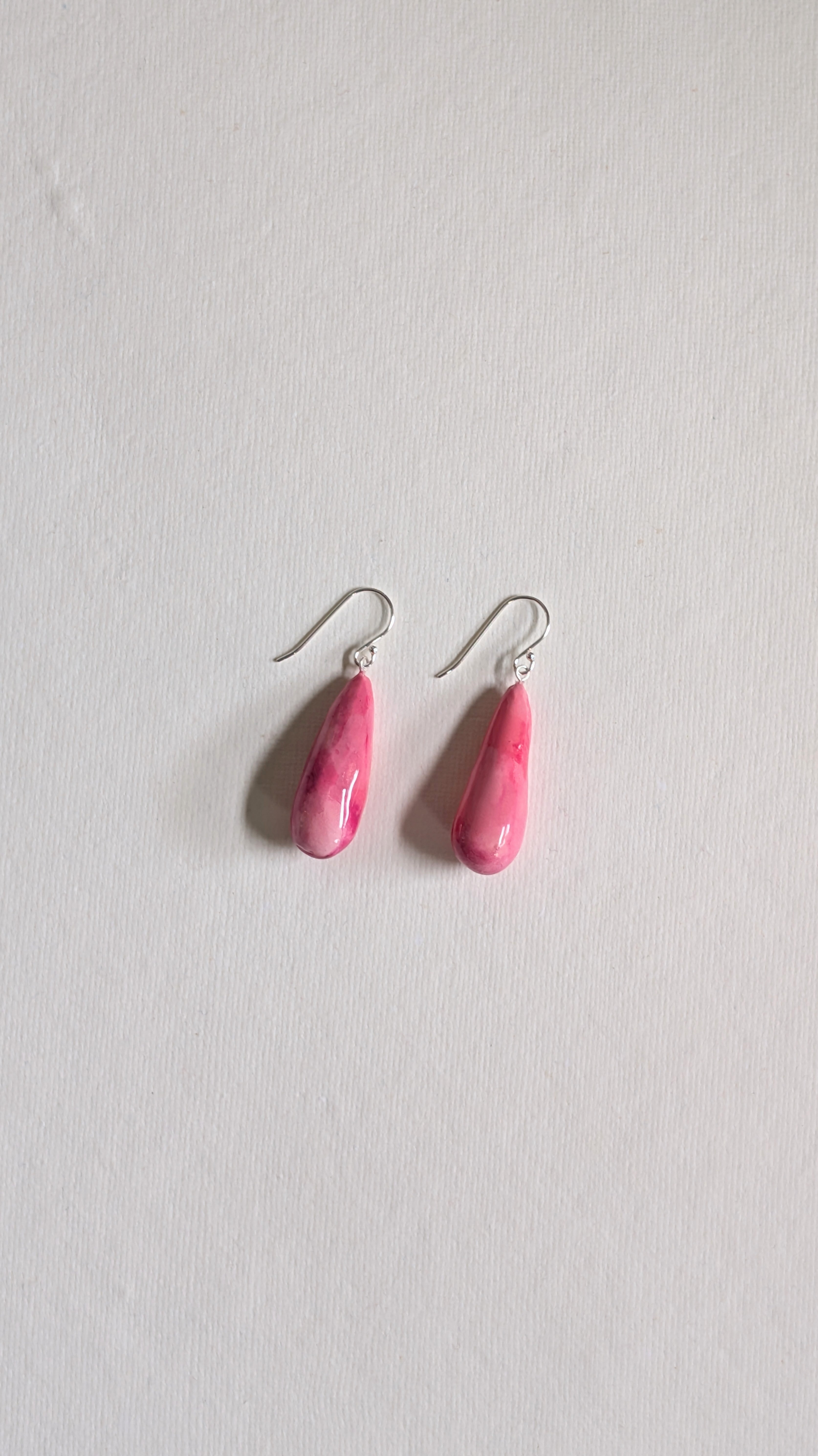 Teardrop shaped handmade ceramic earrings painted in peony pink and finished with sterling silver ear wires.