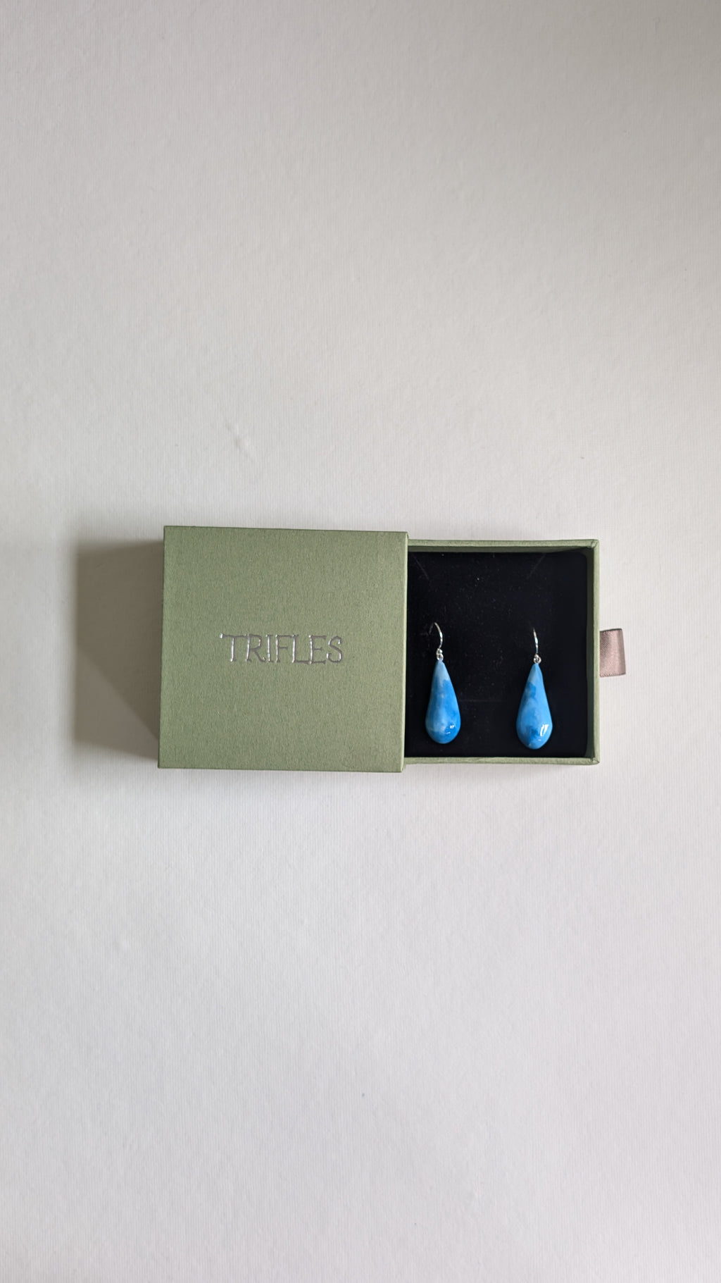 Teardrop shaped handmade ceramic earrings painted in chocolate brown and finished with sterling silver ear wires in Trifles gift box.