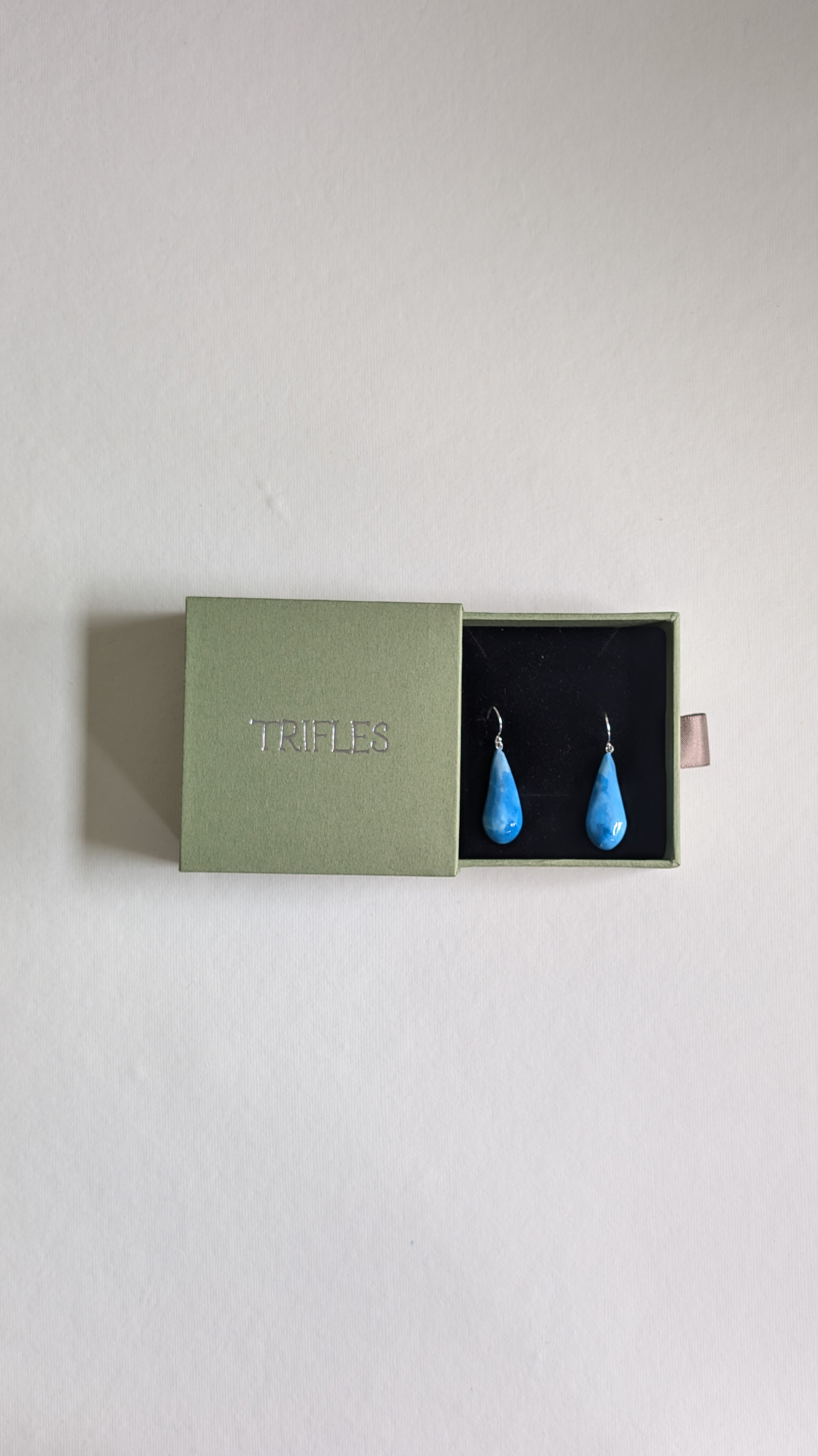 Teardrop shaped handmade ceramic earrings painted in chocolate brown and finished with sterling silver ear wires in Trifles gift box.