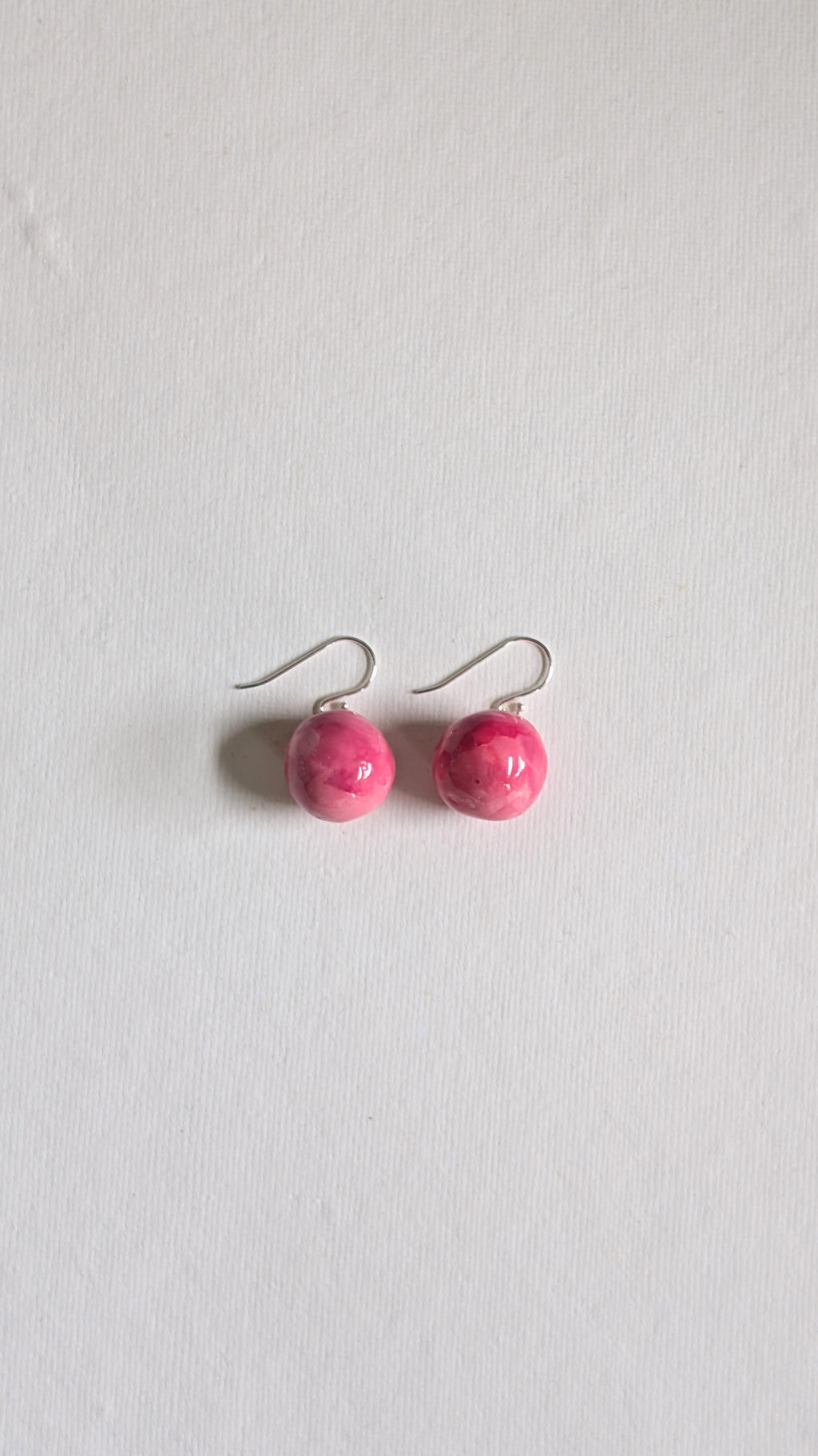 Orb shaped handmade ceramic earrings painted in peony pink and finished with sterling silver ear wires.