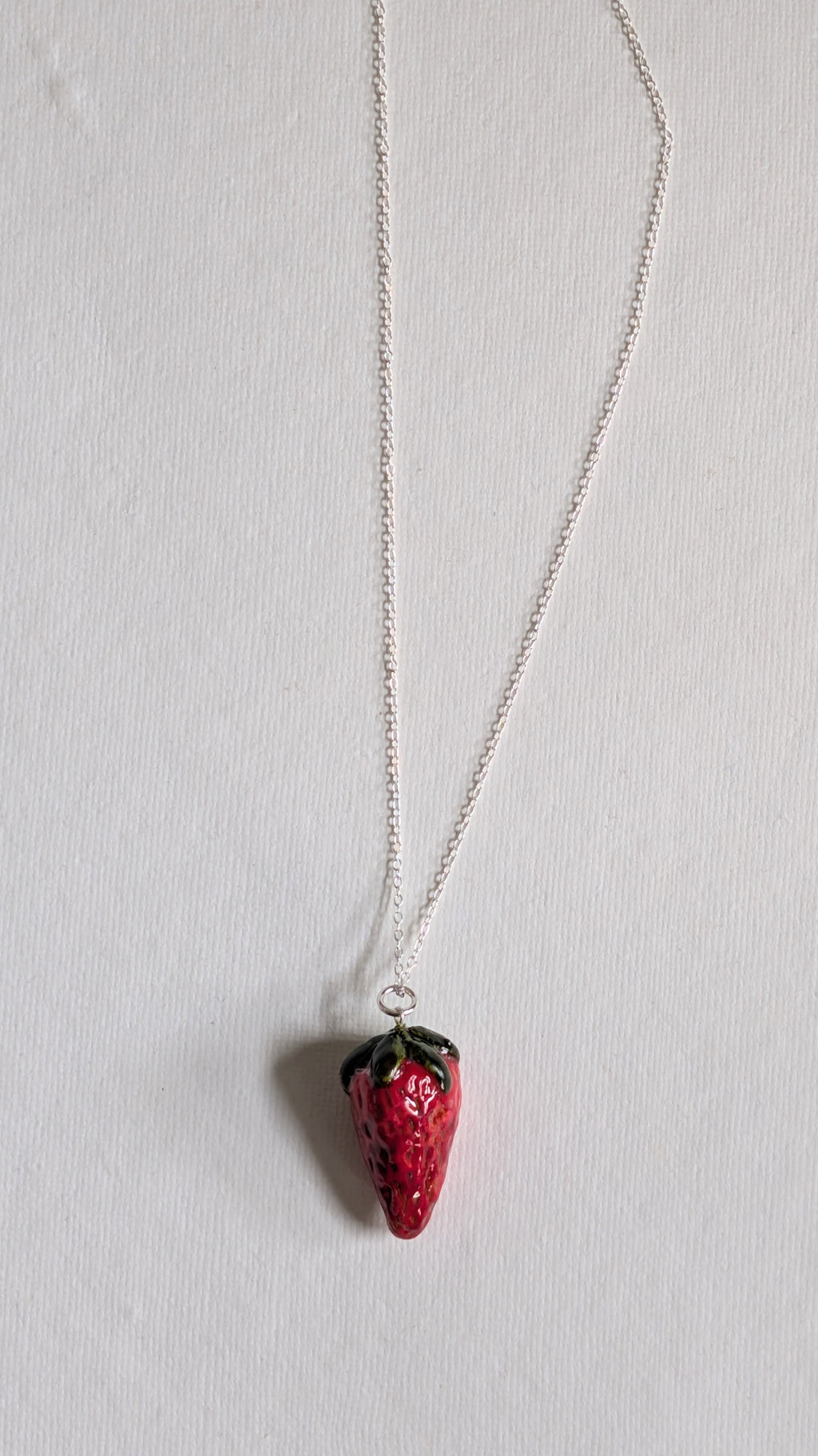 Hand painted ceramic strawberry necklace on sterling silver chain.